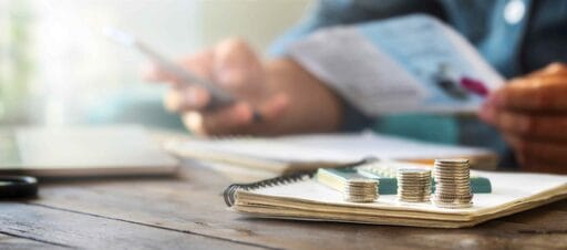 stacks-coins-wooden-table-with-calculator-background-man-checks-household-bills-1-scaled